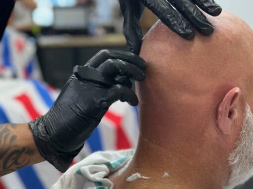 JD Barber Shop Magnolia TX Photo Gallery Close-up of barber shaving a bald client's head at JD Barber Shop.