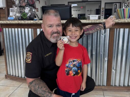 JD Barber Shop Traditional Barber Shop Services in Magnolia, Texas Smiling young boy with a toy badge at JD Barber Shop, kid-friendly grooming services.